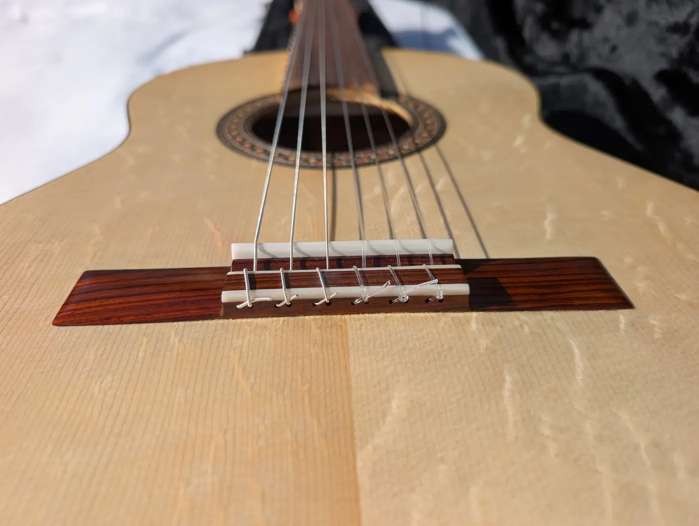 Head-on view along the soundboard showing the six strings dropping steeply from the bone saddle into the tie block