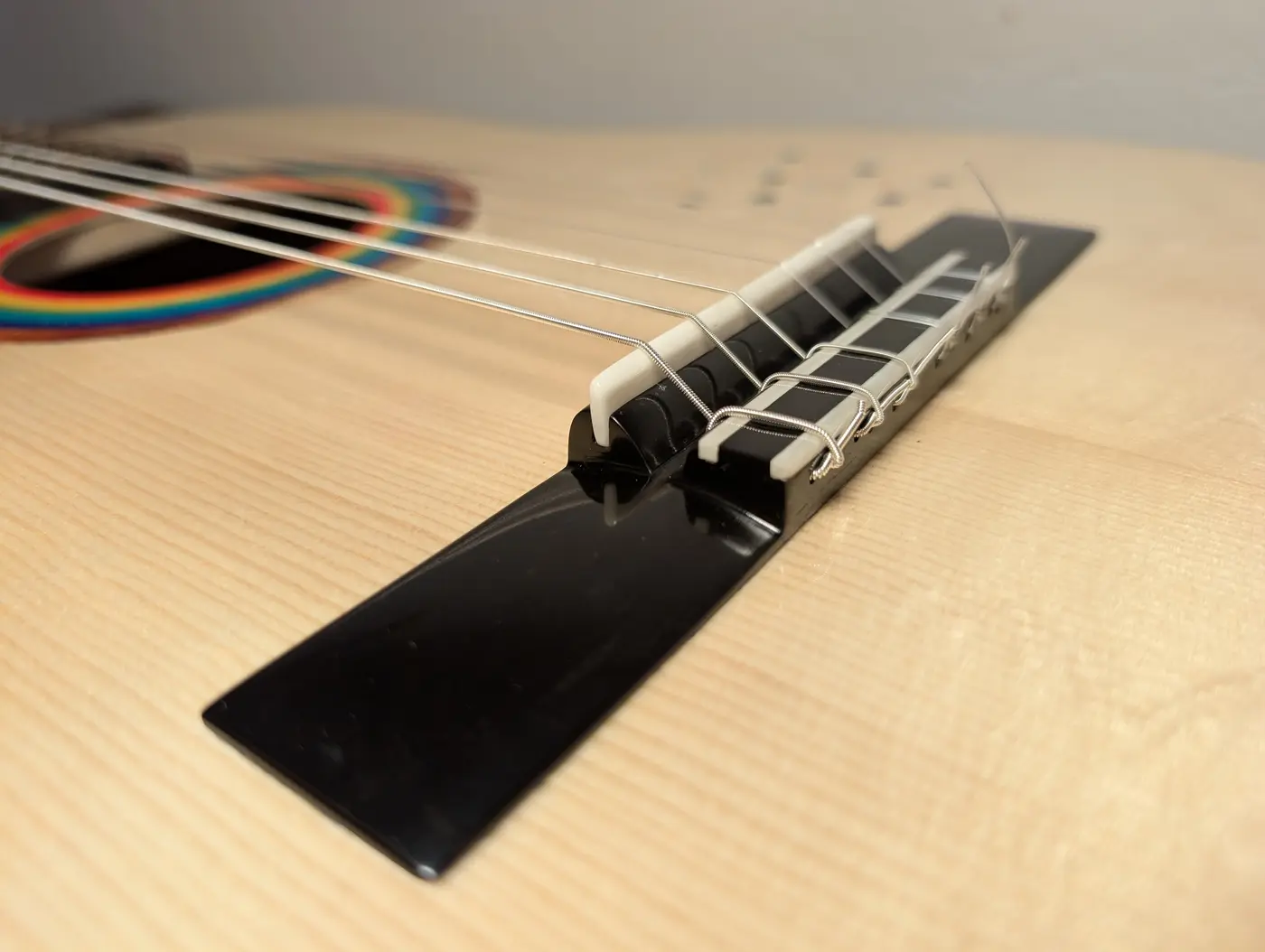 Close view of an ebony tie block, its twelve holes drilled in two rows and the string ends woven back through and tucked upward